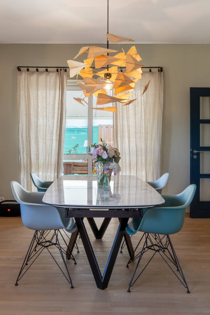 La salle à manger aux tons bleus et gris, éclairé d'une suspension d'avions en papier, par Etymodéco, Magali Brustlein, Décoratrice et Expert Feng Shui à Saint Louis en Alsace