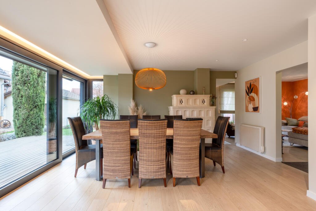 La salle à manger avec le mur kaki en arrière plan et un poêle alsacien, par Etymodéco, Magali Brustlein, Décoratrice et Expert Feng Shui à Saint Louis en Alsace