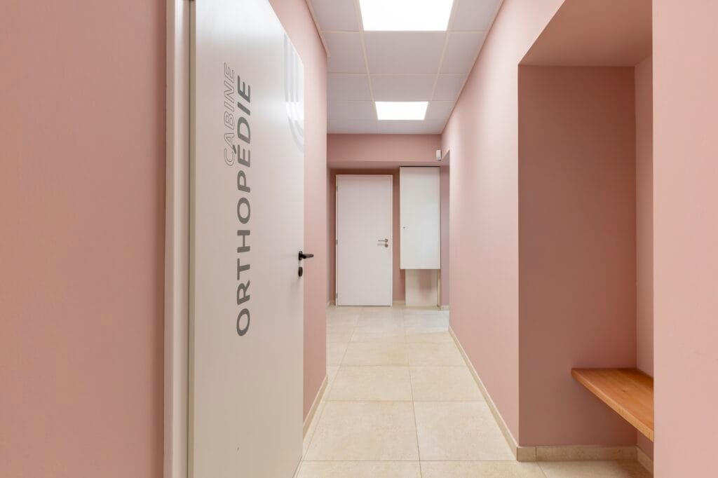 Le couloir repeint en rose poudré avec accès sur la salle de d'orthopédie, par Etymodéco, Magali Brustlein, Décoratrice d'intérieur à Saint Louis en Alsace
