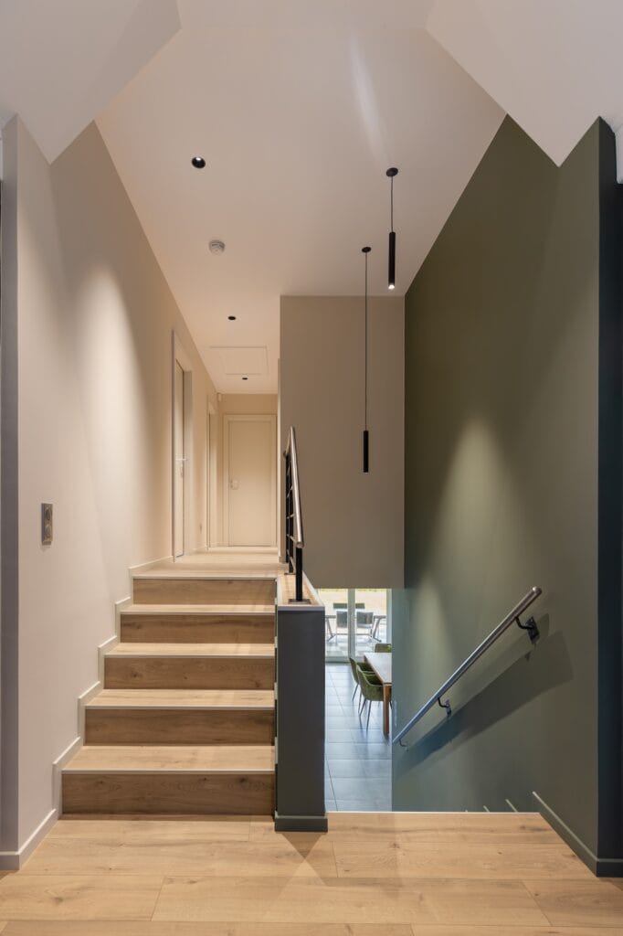 Escalier en bois avec mur vert olive et éclairage suspendu, par Etymodéco, Magali Brustlein, Décoratrice d'intérieur dans le Haut-Rhin