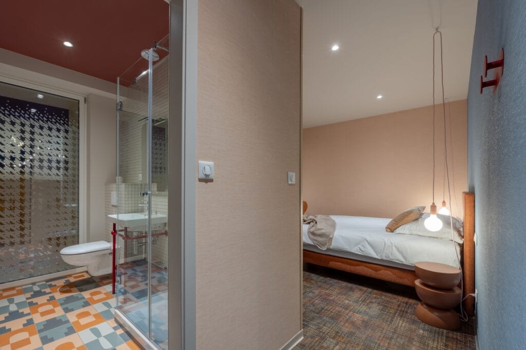 Vue d'ensemble de la chambre avec vue sur la salle de bain avec piètement de lavabo rouge, par Etymodéco, Magali Brustlein, Directrice Artistique à Mulhouse en Alsace