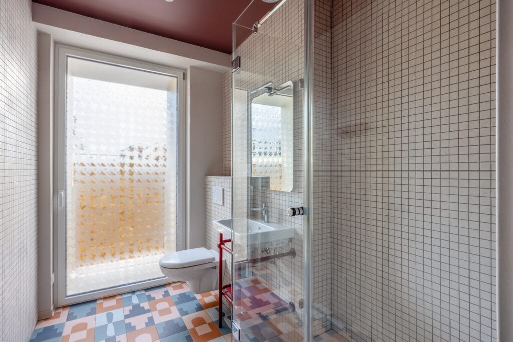 Vue sur la salle de bain avec piètement de lavabo rouge et carreaux de sol à motifs, par Etymodéco, Magali Brustlein, Directrice Artistique à Mulhouse en Alsace