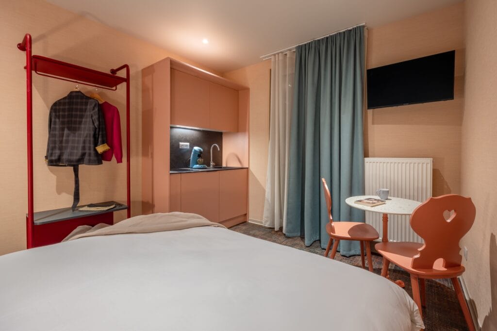 Vue d'ensemble de la chambre avec penderie rouge industrie, la mini cuisine et chaises vieux rose, par Etymodéco, Magali Brustlein, Directrice Artistique à Mulhouse en Alsace