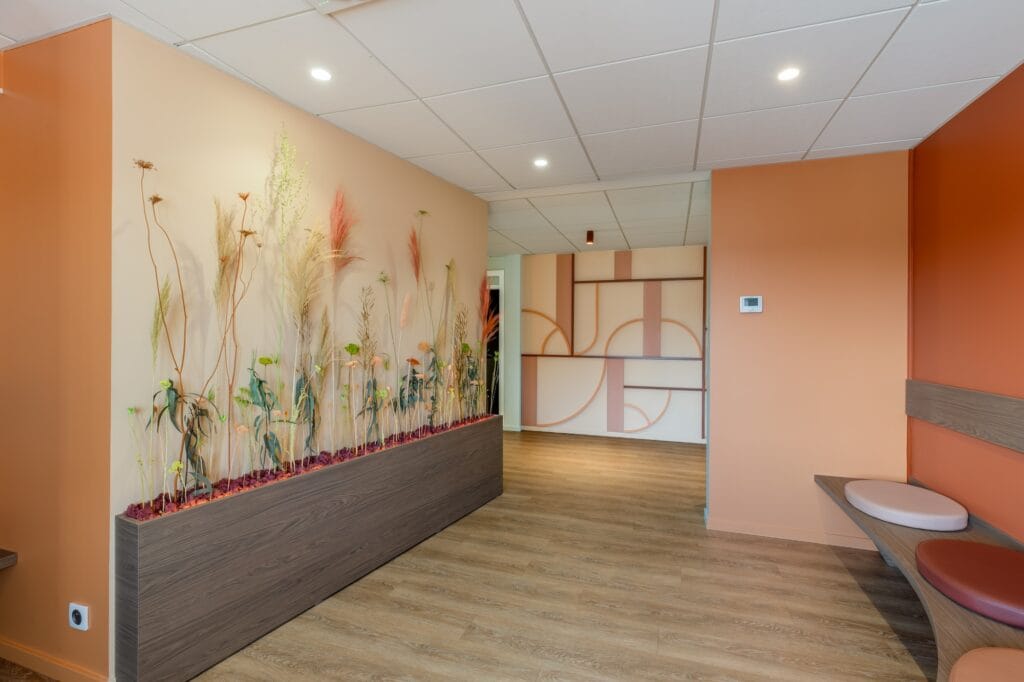 La salle d'attente avec une grande composition florale, le banc périphérique et les assises galettes colorées, par Etymodéco, Magali Brustlein, Décoratrice d'intérieur dans le Haut-Rhin